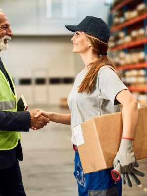 happy-female-warehouse-worker-handshaking-with-company-manager-industrial-storage-compartment-scaled.jpg